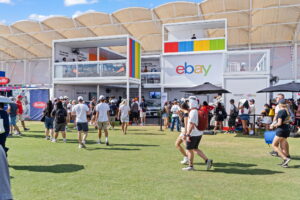 eBay activation stand with logo at Formula 1 fan zone, crowd walking on grass